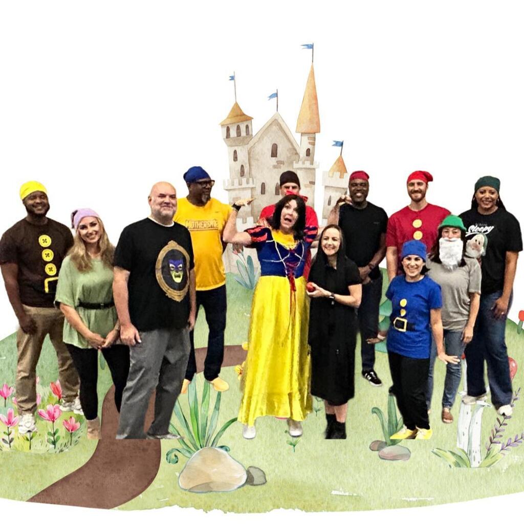 Group of people in costume standing in a field in front of a castle backdrop.