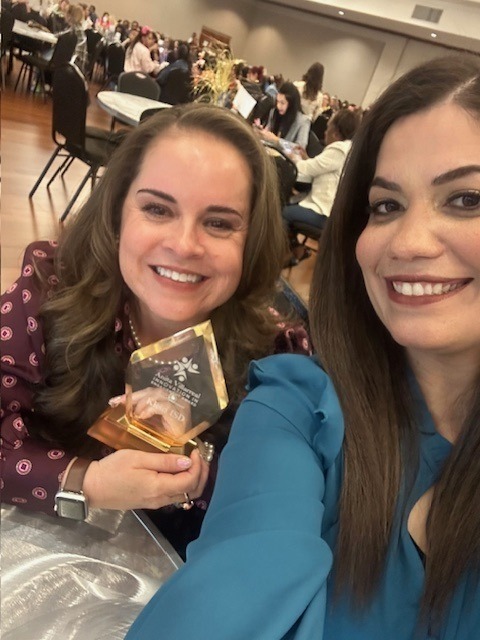 two women posing with award