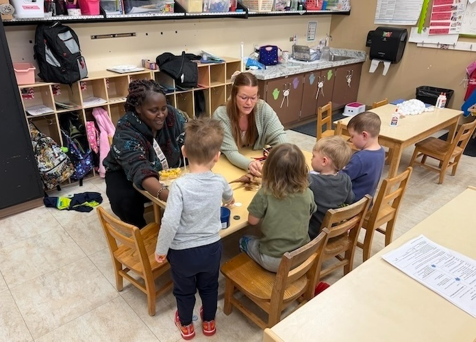 Teacher Robi Magabe and assistant Kayde Moss help a group of preschool children learn to listen and take turns