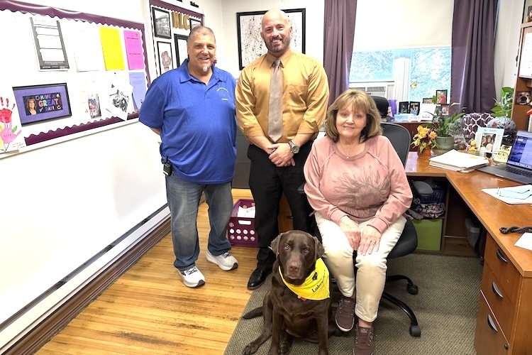 Gracie, a chocolate lab, sits with her owner, Barbara Waite, in Waite’s office at the Knox Learning Center. Joining them are Joe Mazzari, left, Learning Center director, and Derek Fisher, student services principal at the Knox County Career Center. Gracie is the fourth dog to have an unofficial, but highly effective, role with alternative school students.