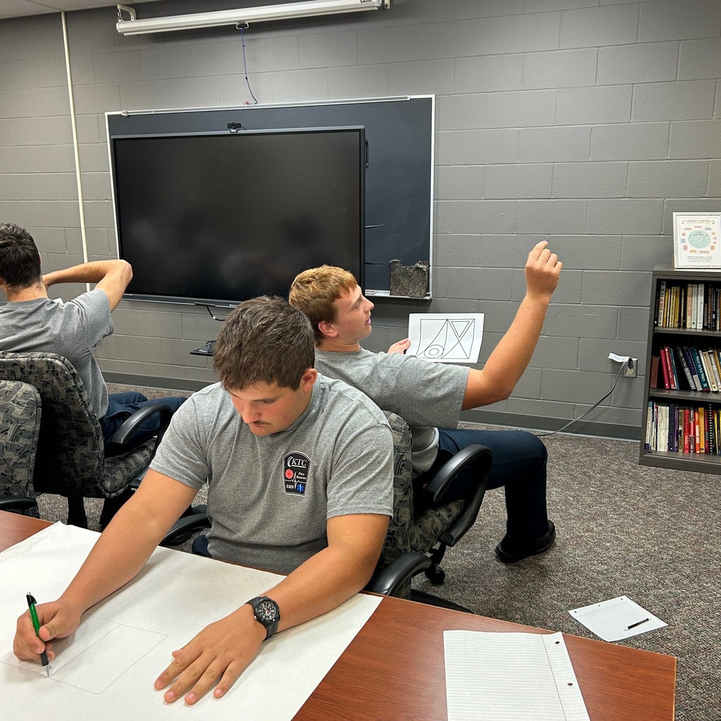 Student drawing on large paper while sitting back to back with another student