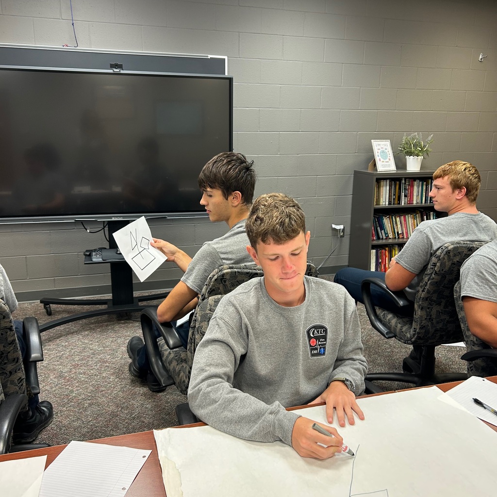 Student drawing on large paper while sitting back to back to another student