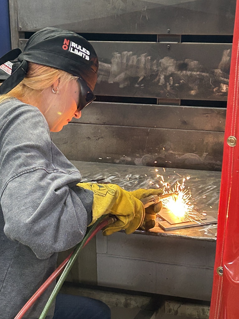 Female welding student using a torch to weld