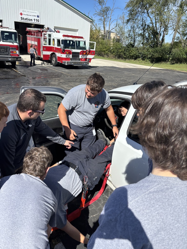EMS trainees practice extricating a patient from a white vehicle onto a backboard outside KTC Station 116.