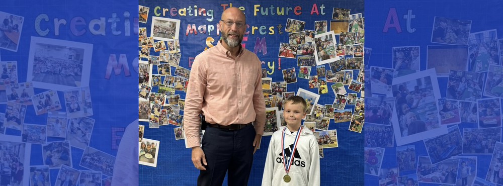 bald man wearing glasses and smiling standing next to male student wearing mathematics medallion