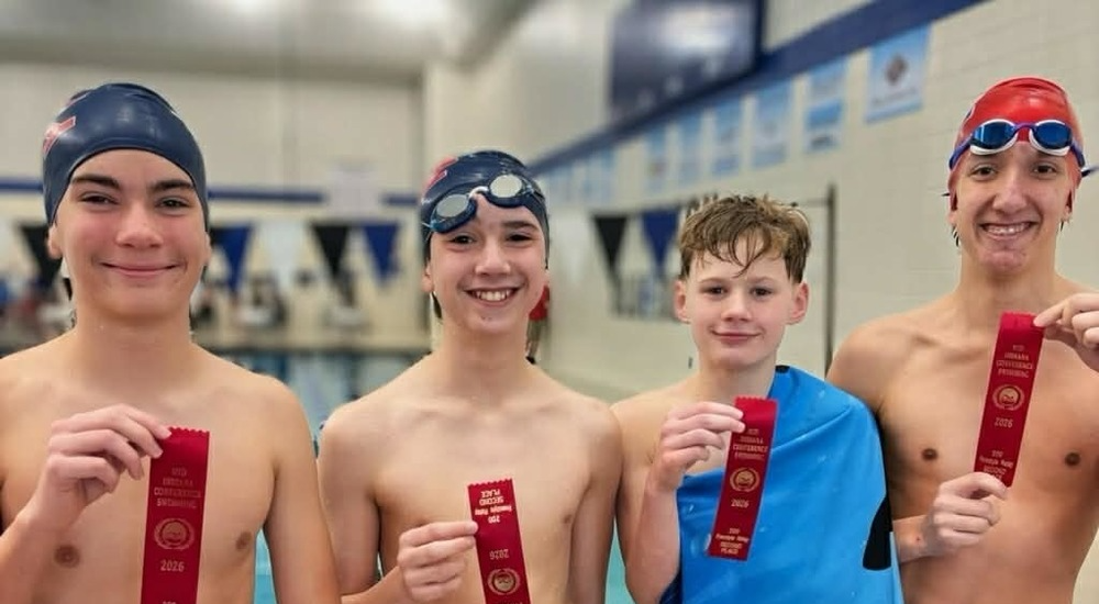 four boys in swimsuits holding second place ribbons