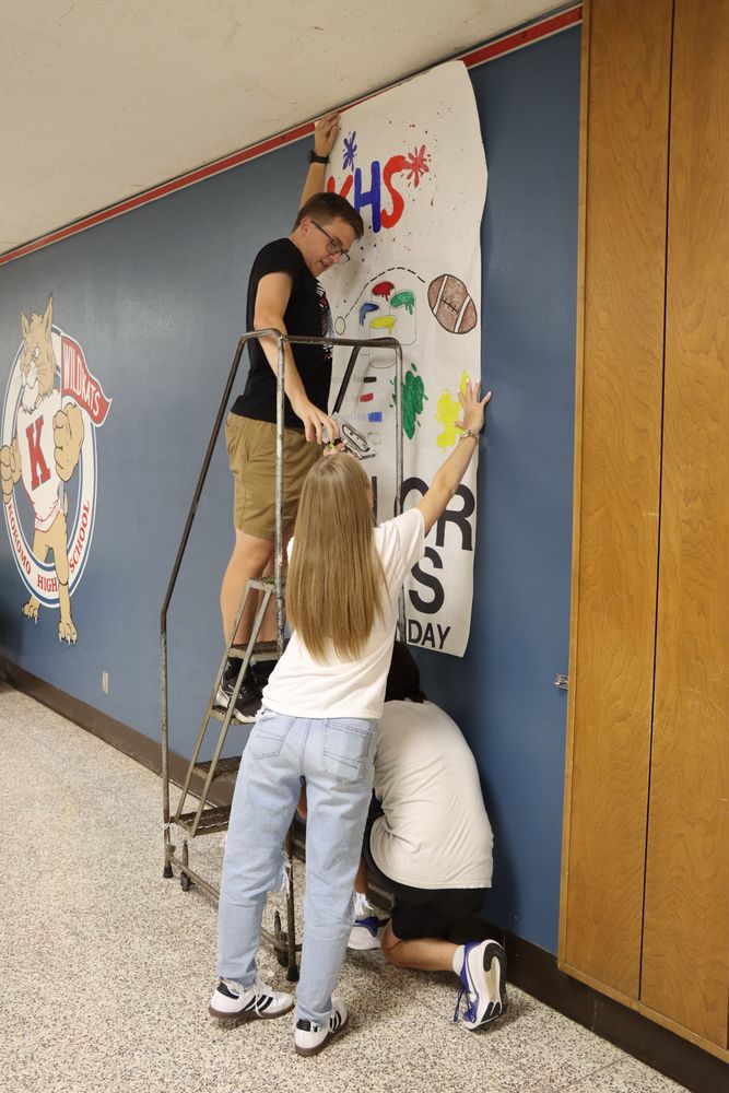 Student Council president Ethan Lytle hangs up posters to decorate for Homecoming week.