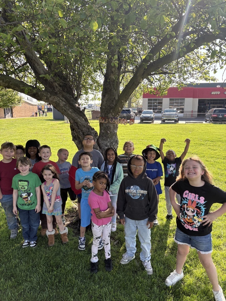 elementary students standing under shade of tree