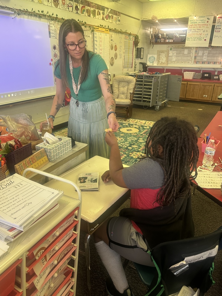 Mrs. Wrightsman hands a student a cracker with dandelion jelly to try.