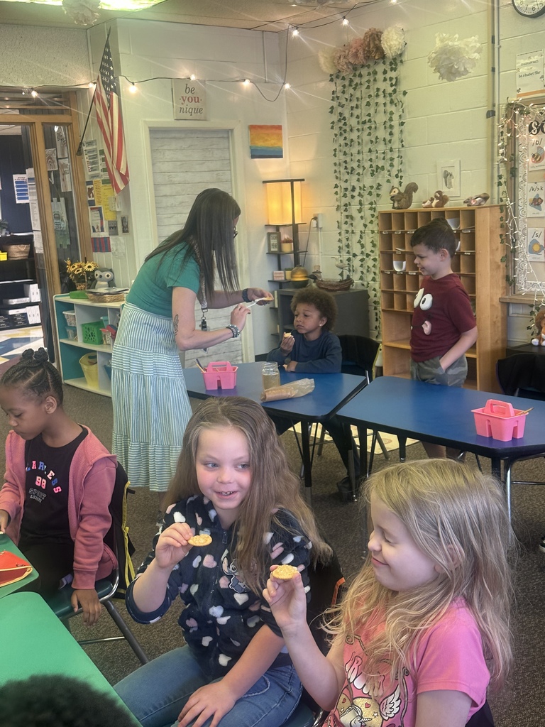 Mrs. Wrightsman hands a student a cracker with dandelion jelly to try.