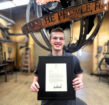 male high school welding student holding letter from President Trump