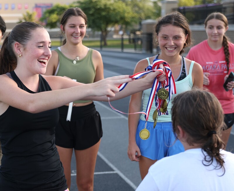 girl receiving medal from high school student athlete
