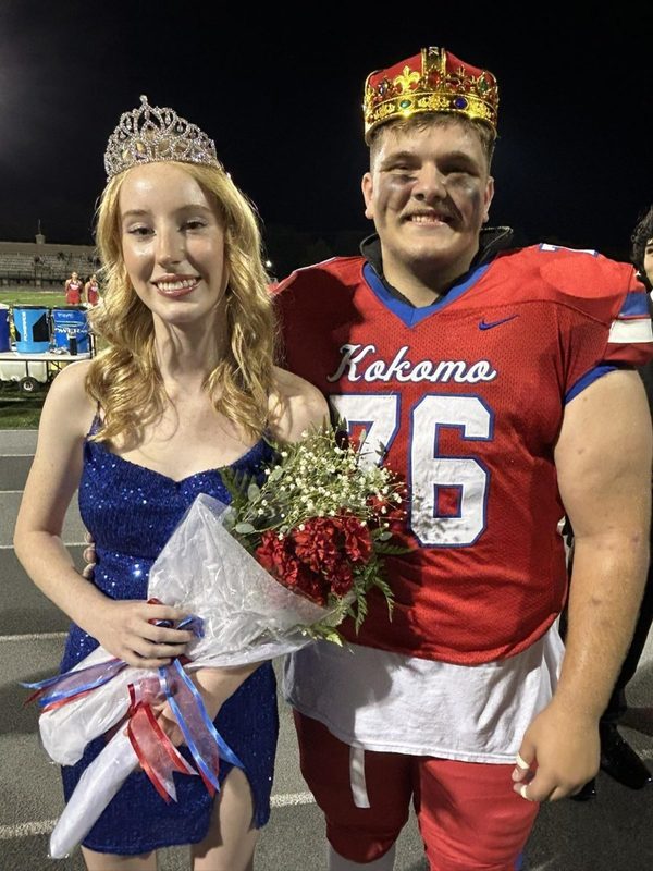 football player and girl in dress both wearing crowns as homecoming king and queen