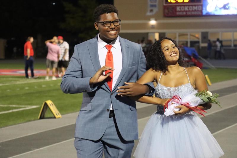 boy in suit with girl in fancy dress holding flowers