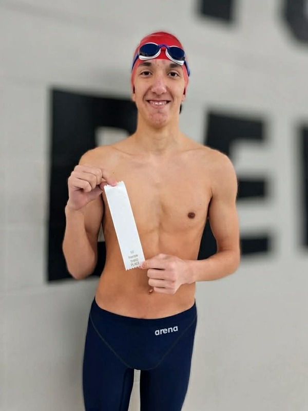 middle school swimmer holding ribbons