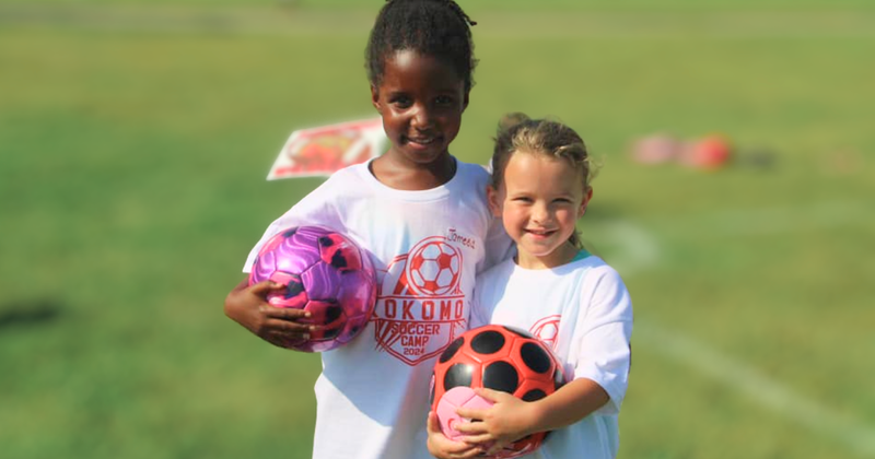 girls holding soccer balls