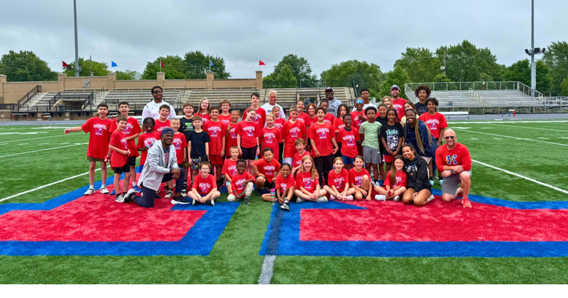 youth sports camp athletes on 50 yard line of football field