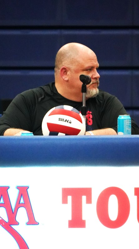 bald man with beard announcing sports on microphone