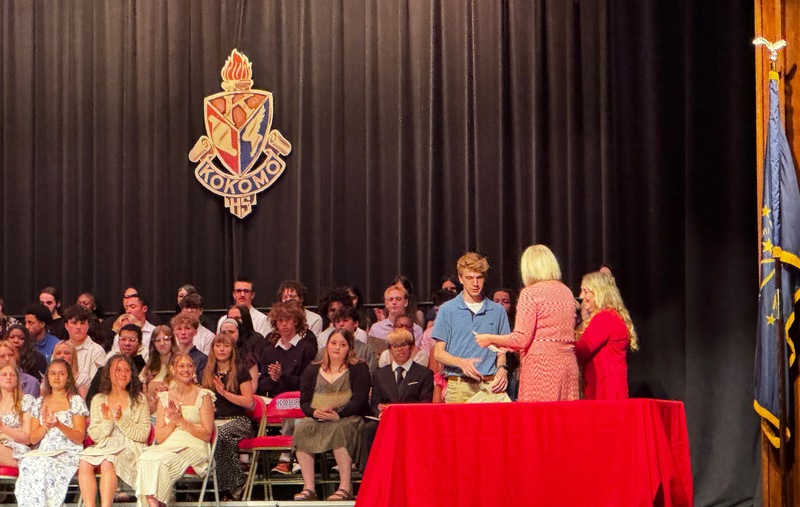 boy accepting certificate on stage with classmates