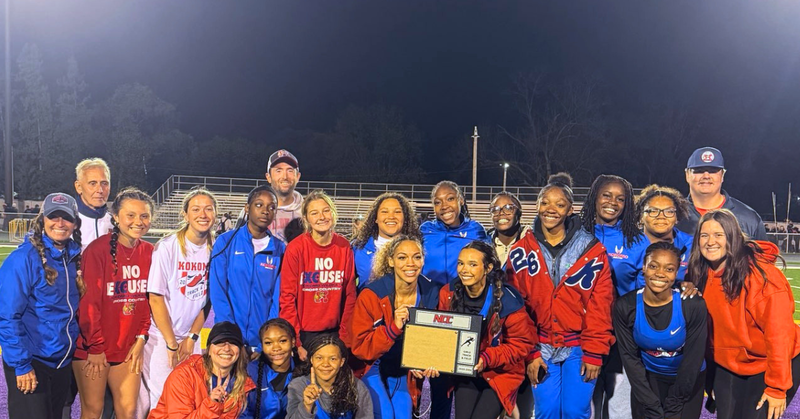 group of high school female athletes with coaches and champion plaque