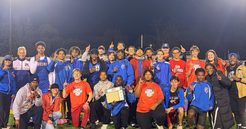 Group of male athletes and coaches holding champion plaque