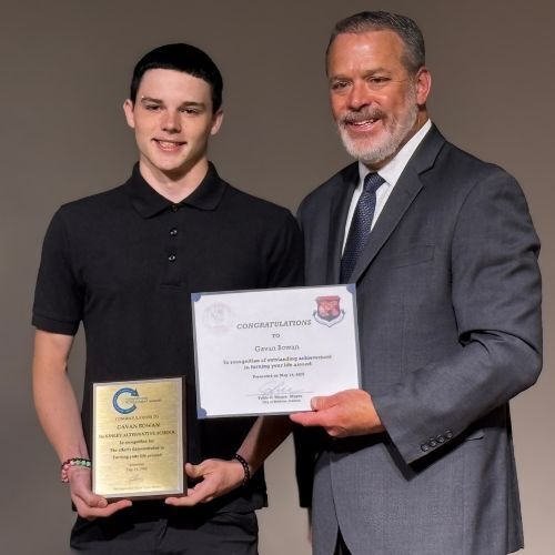 boy holding certificate with city official