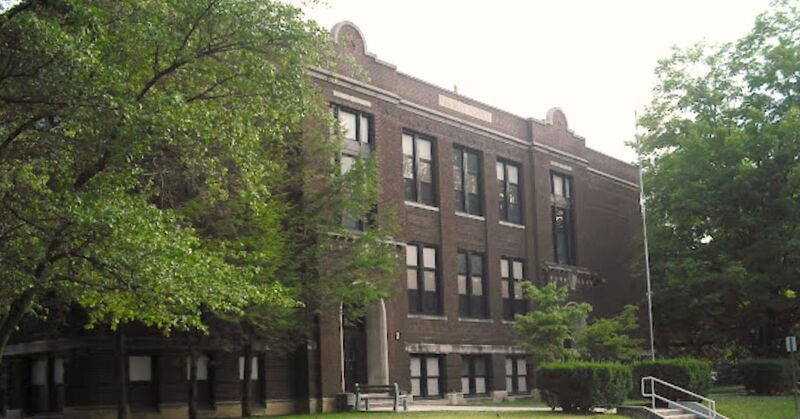 brick school building with trees and green landscaping
