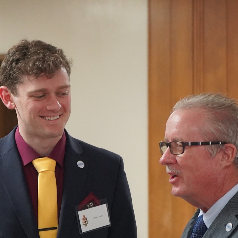 two men standing in conversation smiling