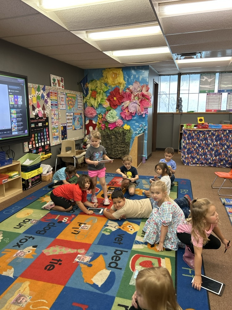 Pre-K students using LCD tablets on the carpet 