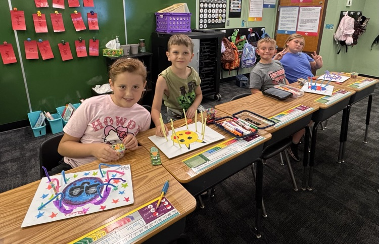Students smiling while working on crafts.