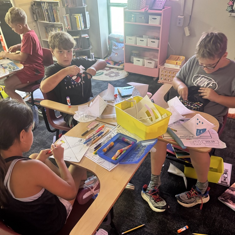 students cutting and glueing paper to form a states of matter pyramid