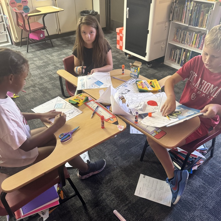 students cutting and glueing paper to form a states of matter pyramid