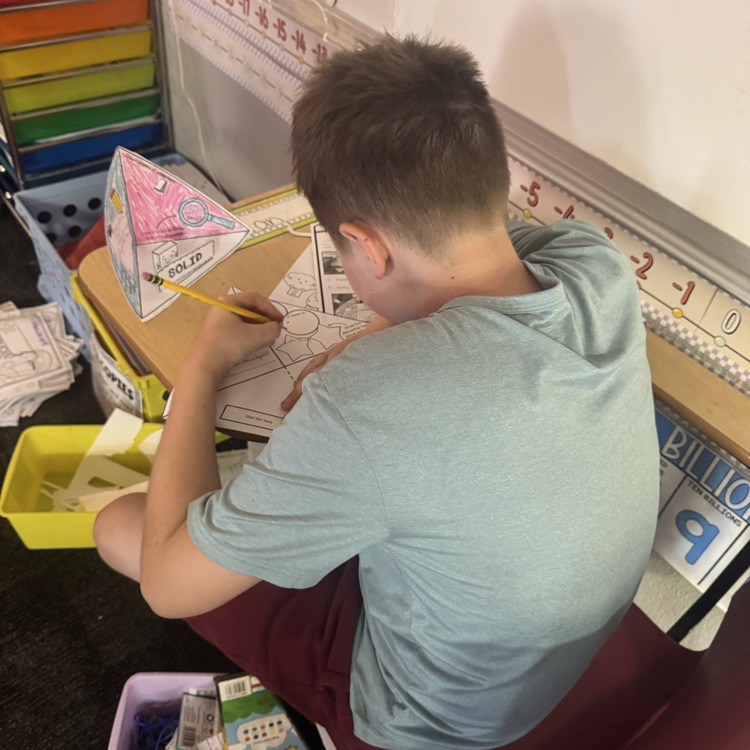 students cutting and glueing paper to form a states of matter pyramid