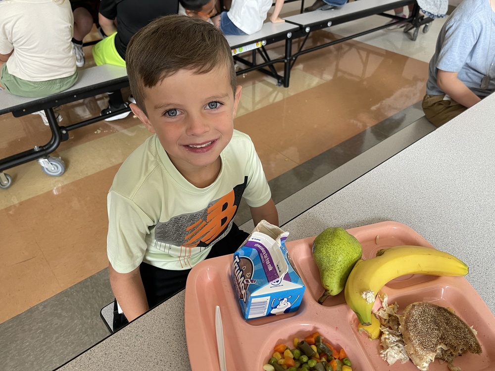darling student sitting in cafeteria with a school lunch