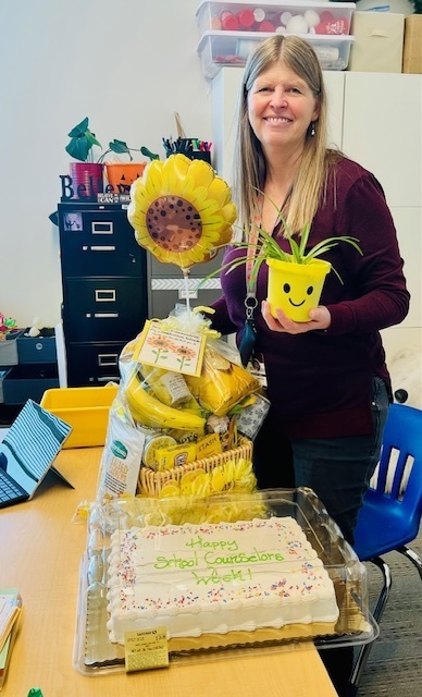 photo of Mrs Dowdy with a cake, balloon and snacks