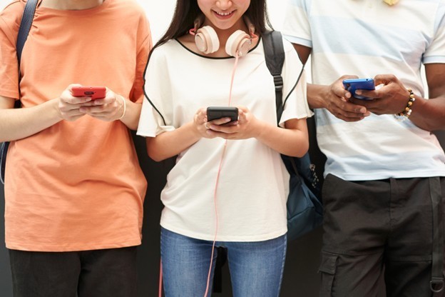 three students on cell phones and headphones