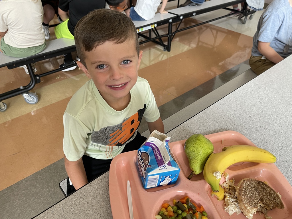 darling student sitting in cafeteria with a school lunch