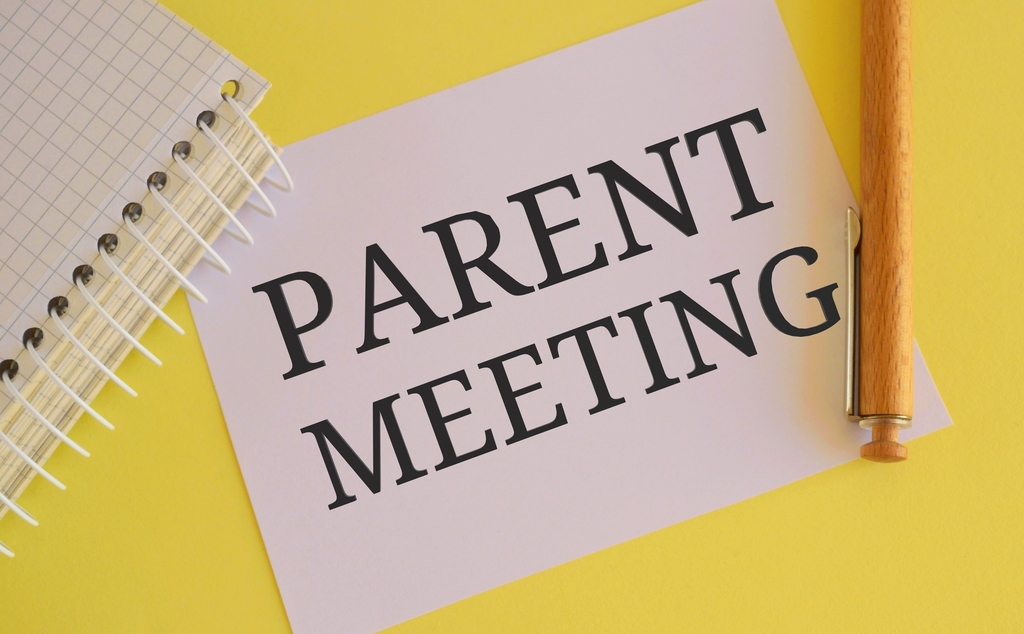 spiral notebook and paper stating parent meeting