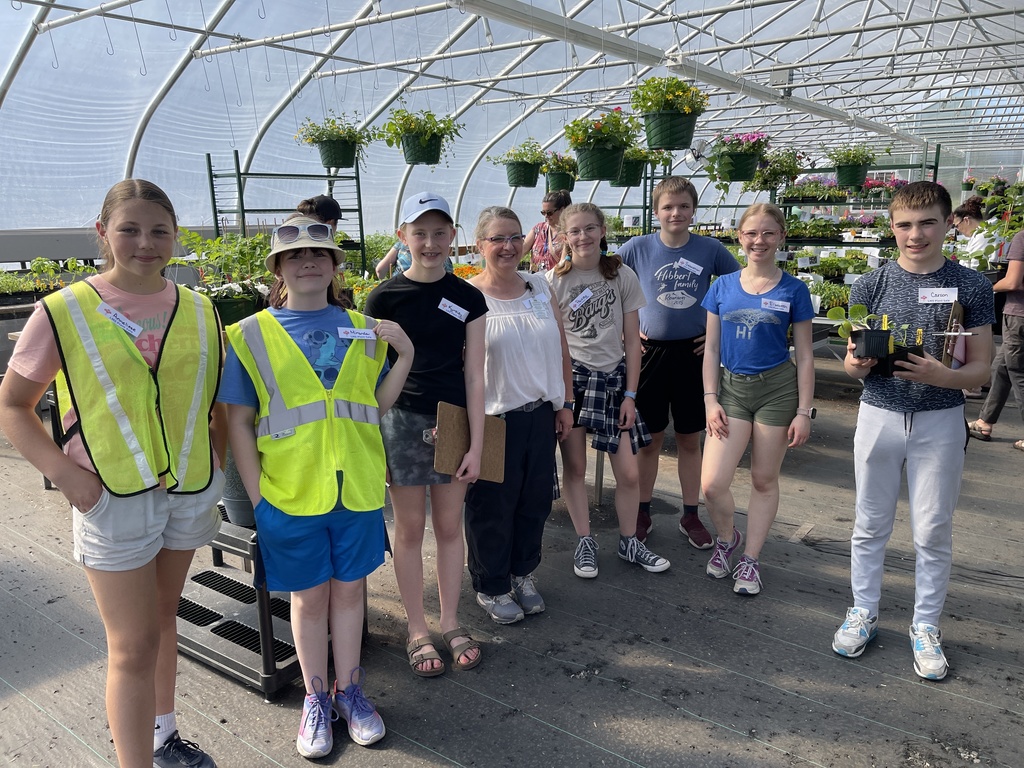 photo of LMS students in the greenhouse holding plants that are for sale