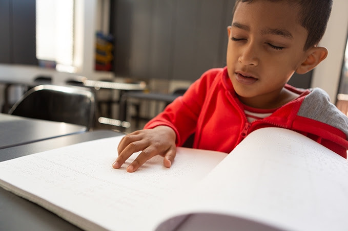 boy reading a braille book