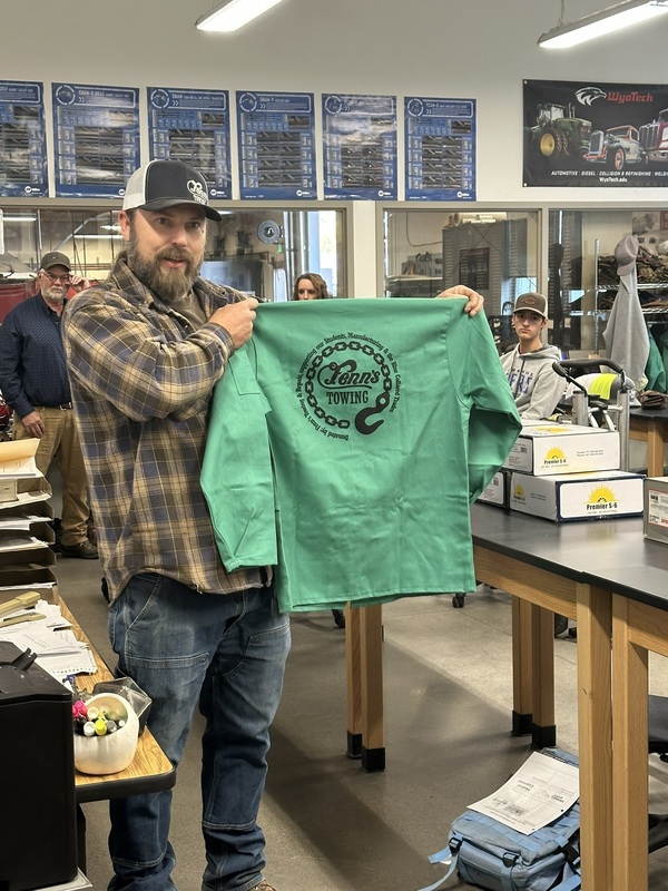 Mr Gisi holding up a new welding jacket with the Fenn's towing logo
