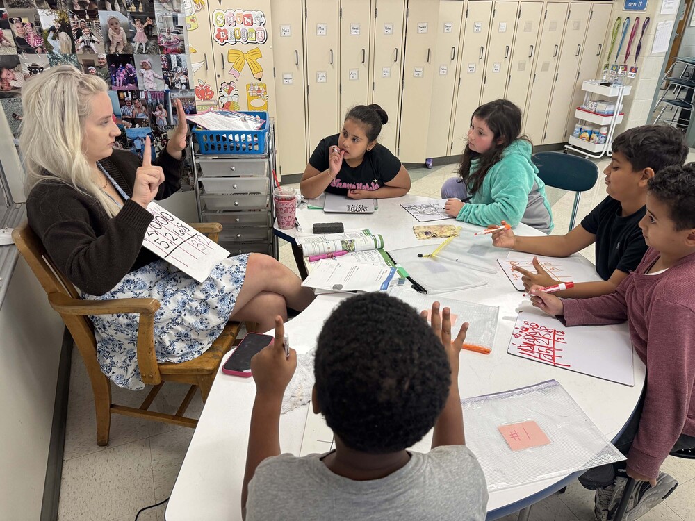 students working on math at table with teacher