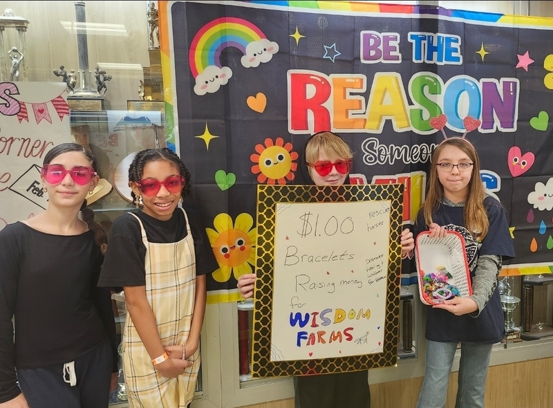 Students hold poster showcasing money raised for Wisdom Farms.
