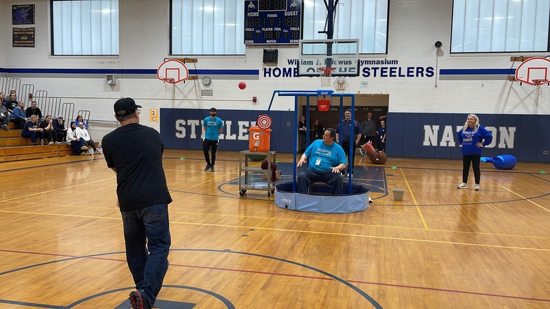 Teacher throws a ball to dunk a staff member with water in the dunk tank.