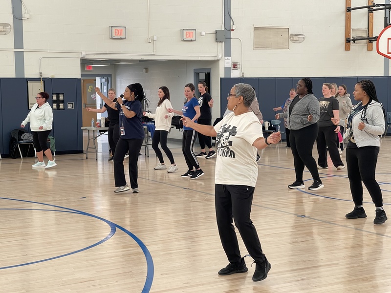 Staff members learn to line dance in the gym.