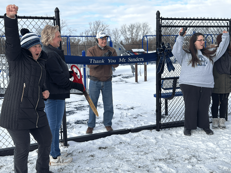 Mr. Sanders cuts the ribbon for the new playground.