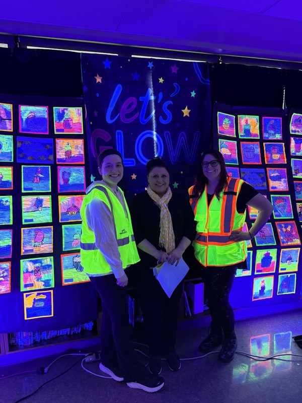 Truman principal and teachers pose for a photo with glowing outfits.
