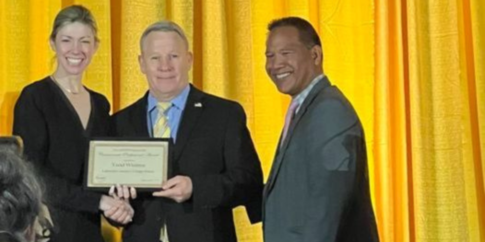 Mr. Whitney onstage holding a certificate with representatives of the Principals Conference