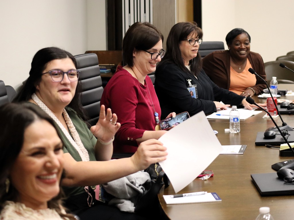 Five female employees laugh during the Employee Advisory Council meeting.