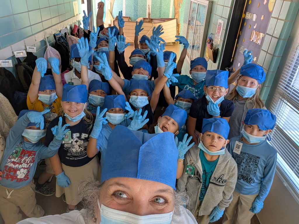 Teacher and students take a picture together dressed as doctors. 